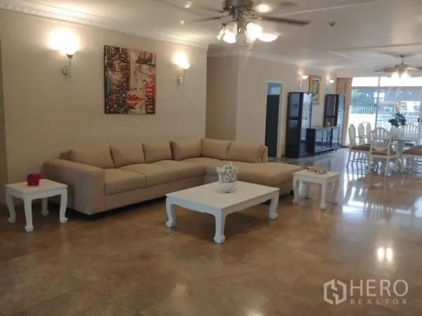 Condominium for rent in Watthana, Bangkok - Spacious open-plan living room with beige L-shaped sofa, marble floors and ceiling fans at Grand Ville House 2.