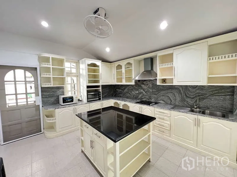 Detached House for rent in Chatuchak, Bangkok - White U-shaped kitchen with central island, stone backsplash and stainless hood.