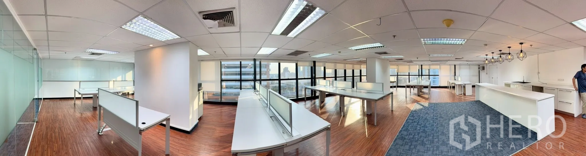 ออฟฟิศ for rent in Watthana, Bangkok - มุมกว้างพื้นที่ทำงานเปิดพร้อมโต๊ะสีขาว กระจกบานใหญ่ พื้นลายไม้ และวิวเมือง.