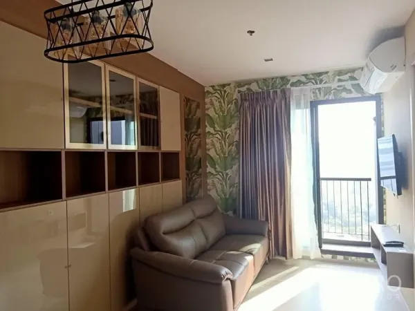 Condominium for rent in Pathum Wan, Bangkok - Bright living room with leather sofa, built-in cabinets, tropical wallpaper and a door to the balcony.