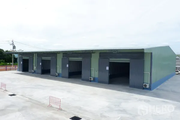 Warehouse for rent in Pak Kret, Nonthaburi - Row of new warehouse units with wide roller doors and a large truck-friendly concrete yard.