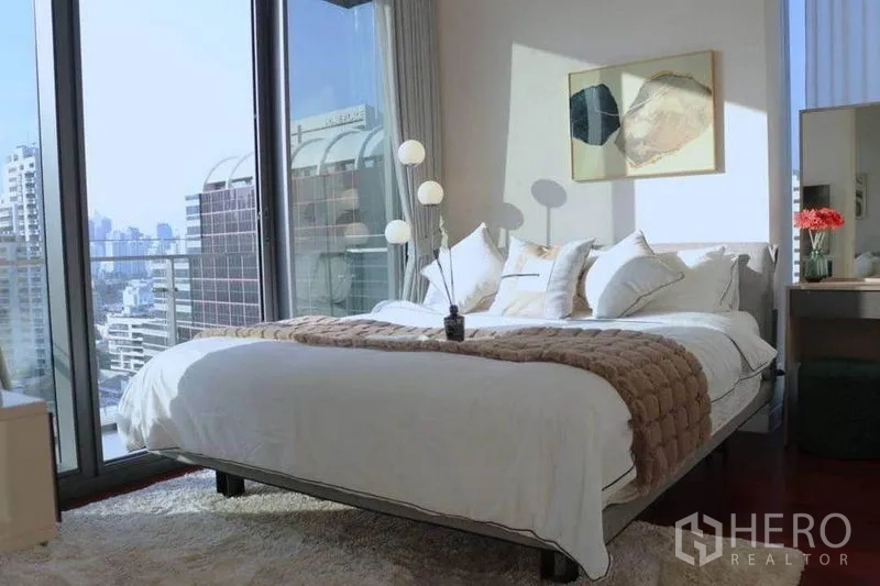 公寓 出租在Watthana, Bangkok - 采光充足的卧室，白色床品，临全景玻璃与城市景观。