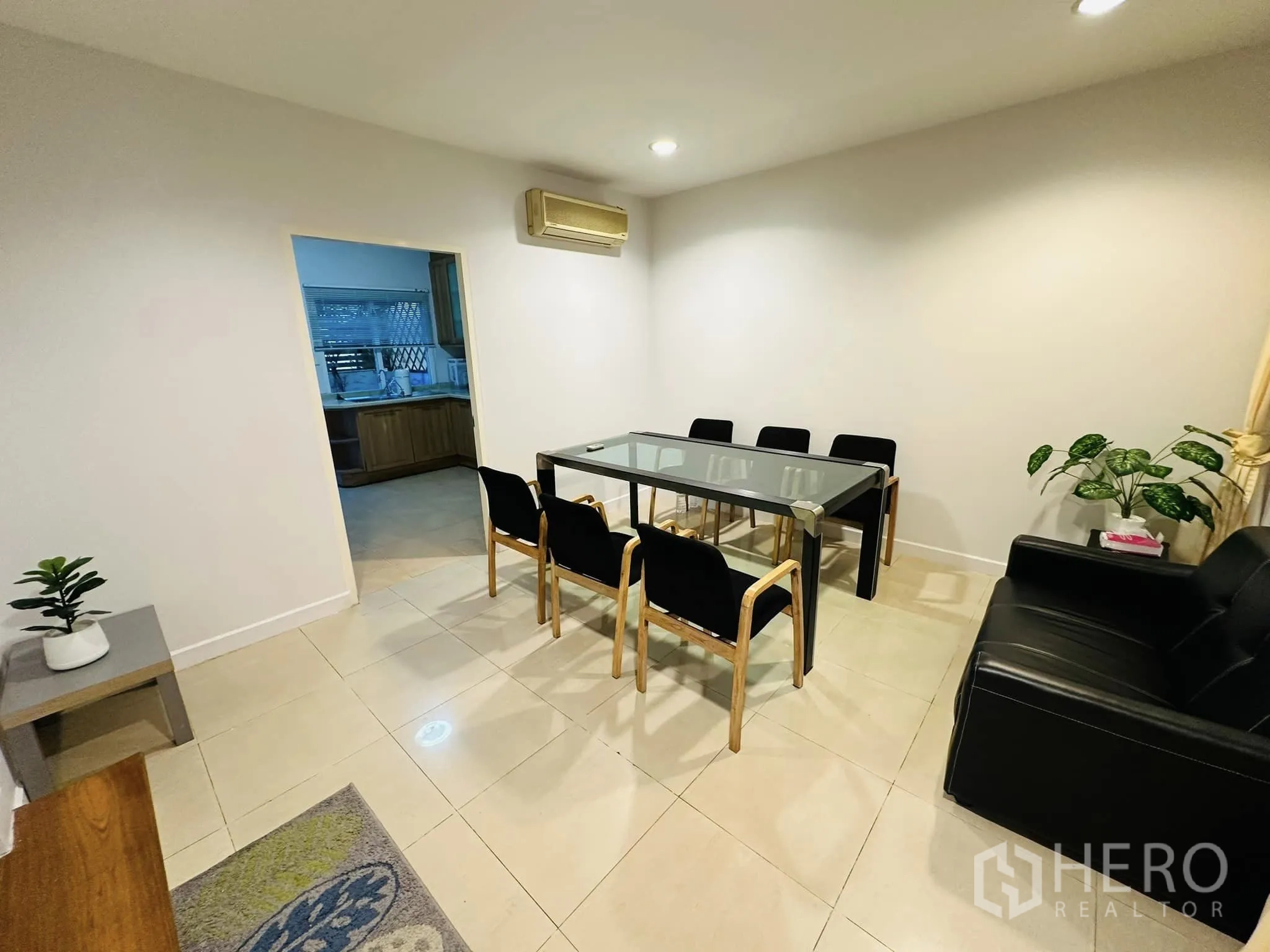 Townhouse for rent in Watthana, Bangkok - Bright secondary dining or meeting room with tile floor, glass table, and open doorway to the kitchen.