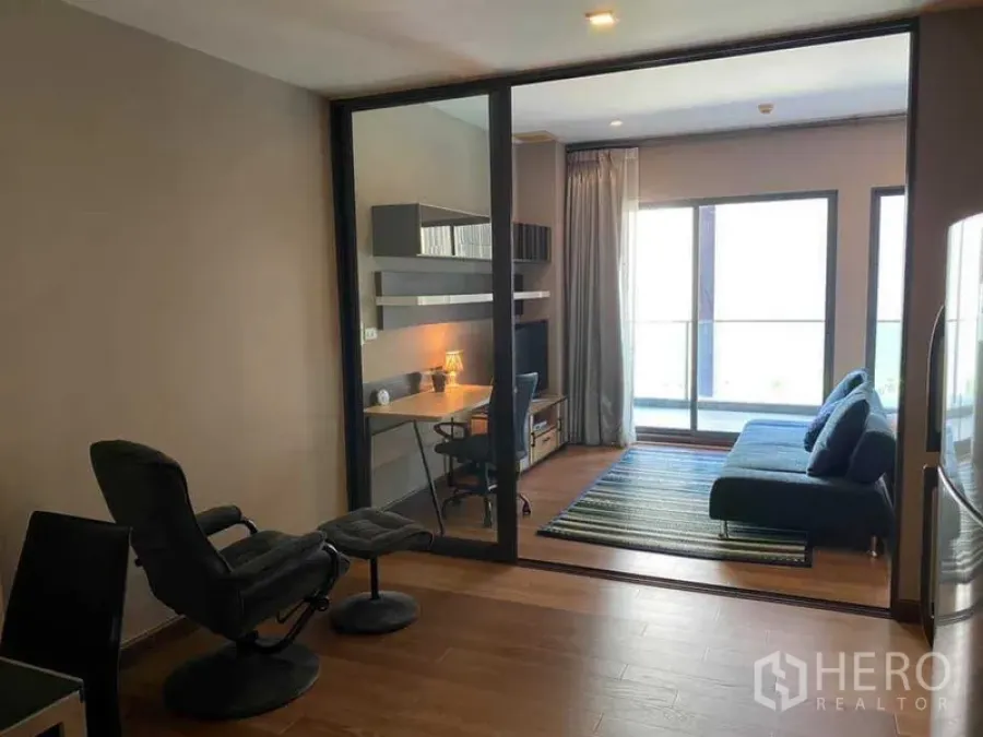 คอนโด ให้เช่าในKhlong Toei, Bangkok - ห้องนั่งเล่นกั้นกระจก โซฟาสีน้ำเงิน โต๊ะทำงาน และประตูระเบียง แสงธรรมชาติ