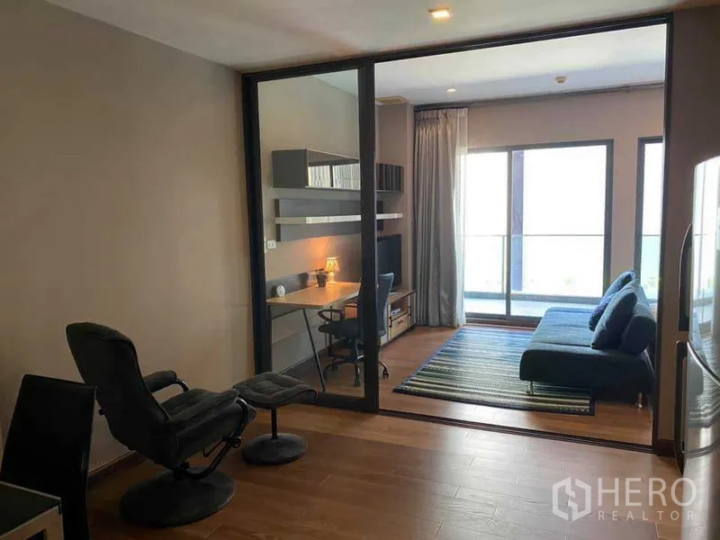 คอนโด ให้เช่าในKhlong Toei, Bangkok - ห้องนั่งเล่นกั้นกระจก โซฟาสีน้ำเงิน โต๊ะทำงาน และประตูระเบียง แสงธรรมชาติ