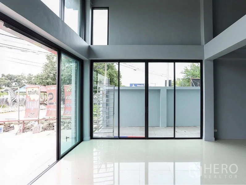 Shophouse for sale in Lam Luk Ka, Pathum Thani - Double-height lobby with corner glazing and sliding doors to the front patio.