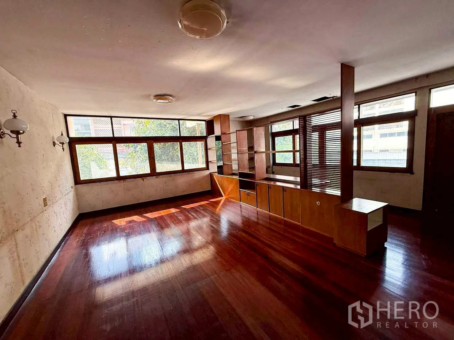 Home Office for rent in Bang Rak, Bangkok - Sunlit workspace with built-in wooden cabinets and expansive windows.