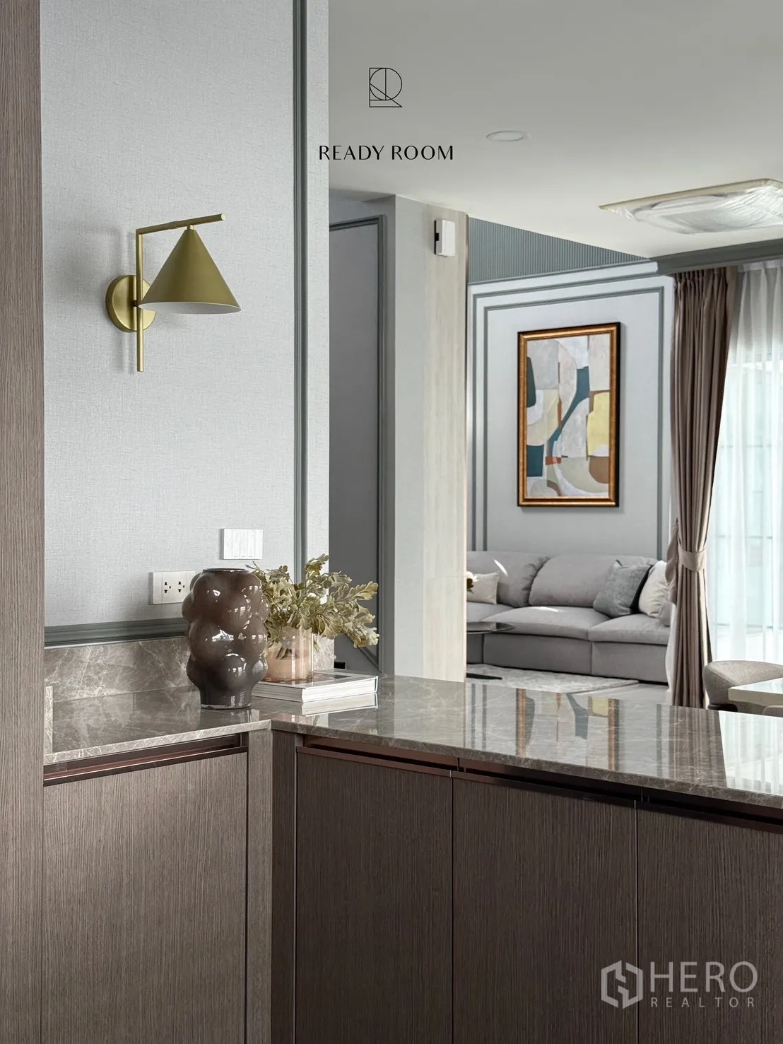 บ้าน ให้เช่าหรือขายในBang Phli, Samut Prakan - เคาน์เตอร์บาร์หินอ่อนพร้อมโคมไฟติดผนังสีทอง มองเห็นห้องนั่งเล่นโซฟาสีเทา