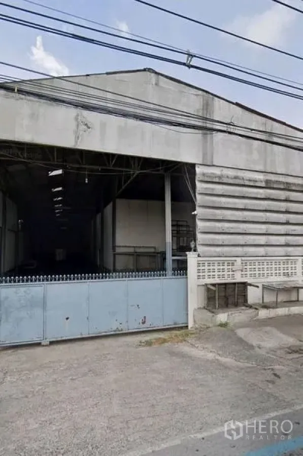 คลังสินค้า ให้เช่าในPathum Thani - ด้านหน้าโกดังพร้อมประตูบานเลื่อนกว้างและทางเข้าคอนกรีต ในอำเภอเมืองปทุมธานี