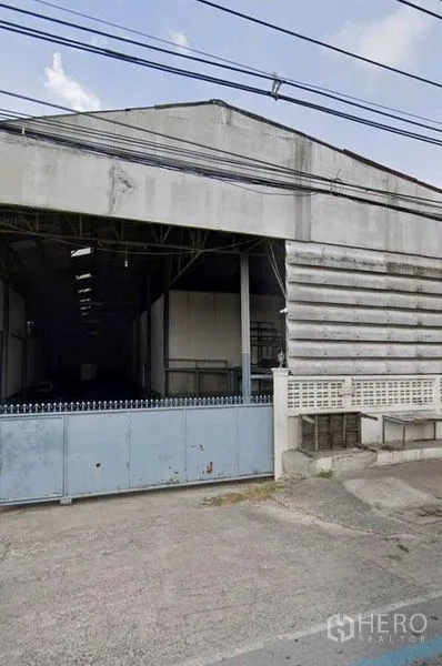 คลังสินค้า ให้เช่าในPathum Thani - ด้านหน้าโกดังพร้อมประตูบานเลื่อนกว้างและทางเข้าคอนกรีต ในอำเภอเมืองปทุมธานี
