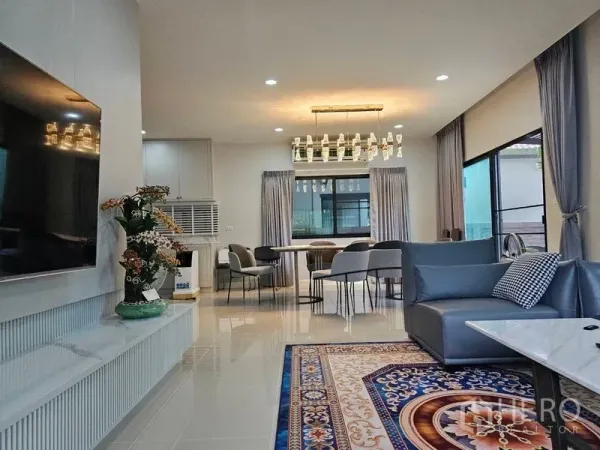 บ้าน ให้เช่าหรือขายในLam Luk Ka, Pathum Thani - ห้องนั่งเล่นเชื่อมพื้นที่ทานอาหาร โคมไฟระย้า โซฟาสีเทา