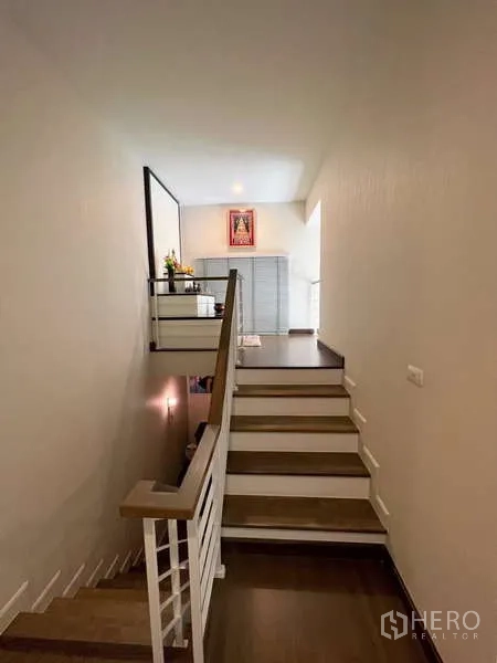 Detached House for sale in Prawet, Bangkok - Wood staircase and landing with railing leading to an upper sitting area filled with natural light.
