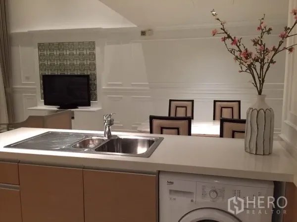 公寓 出租在Sathon, Bangkok - 开放式厨房配水槽与洗衣机，餐桌面向电视的曼谷公寓。