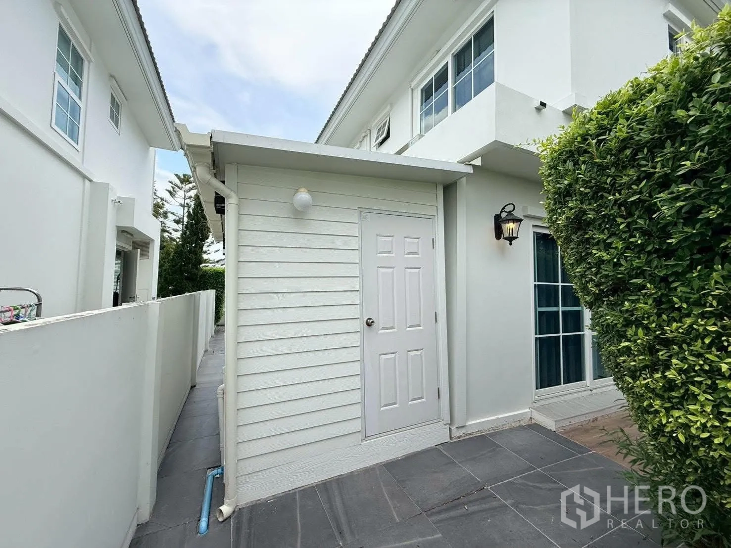 Detached House for rent in Bang Phli, Samut Prakan - Exterior view of a small side room with tiled walkway and hedges.