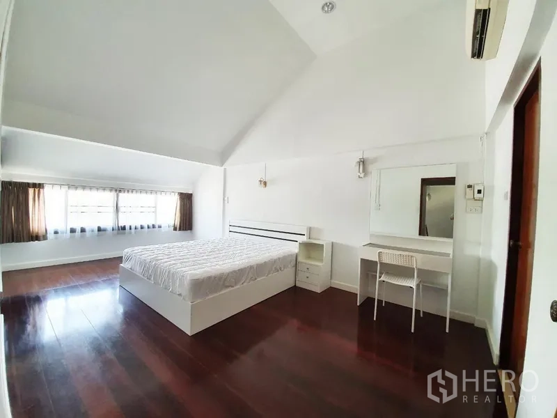 บ้าน ให้เช่าในPhra Khanong, Bangkok - ห้องนอนเพดานสูง พื้นไม้เข้ม หน้าต่างบานยาวรับแสง เตียงและโต๊ะเครื่องแป้ง