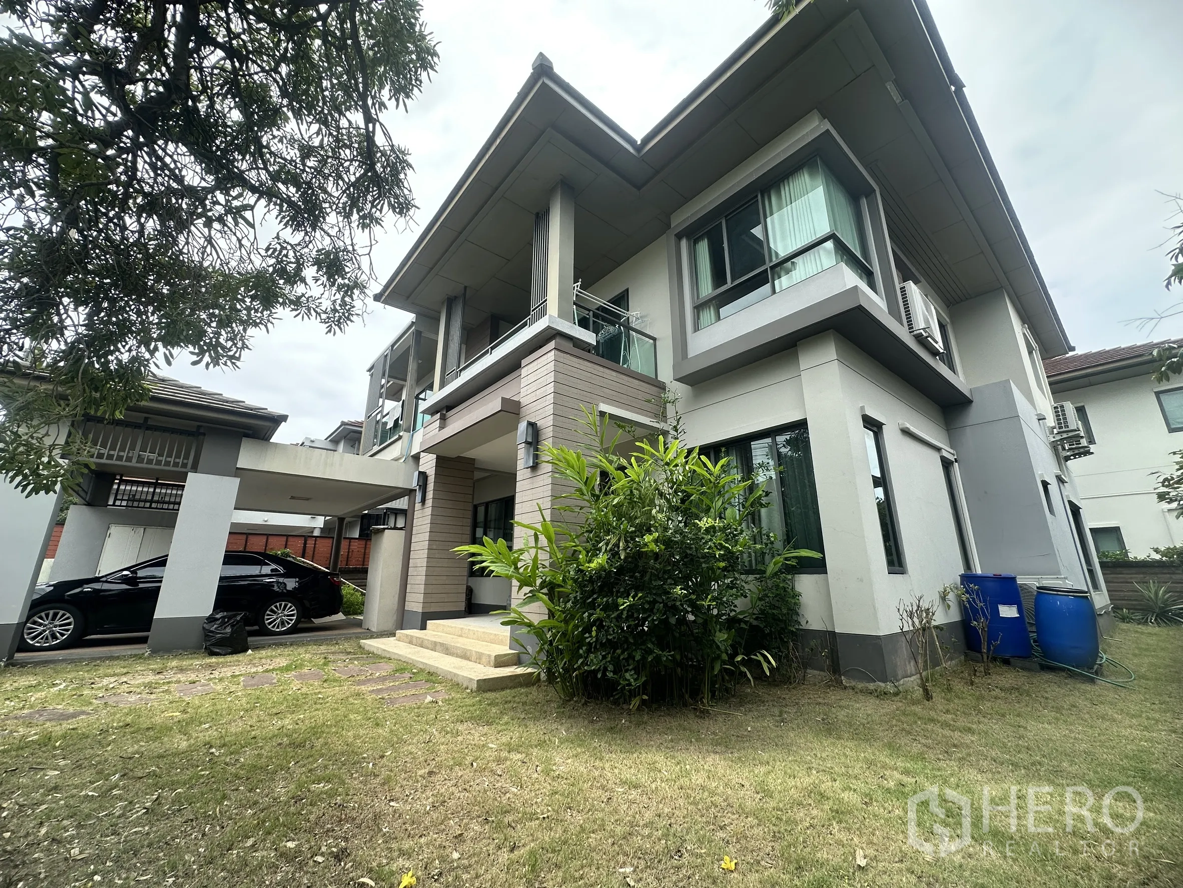 Detached House for sale in Pak Kret, Nonthaburi - Side view showing carport, lawn garden, and modern facade.