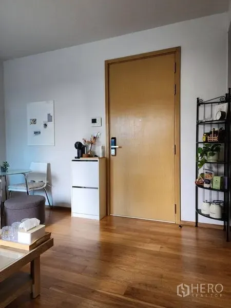 公寓 出租在Watthana, Bangkok - 入户区带木门、小型收纳柜与开放置物架，木地板温馨。
