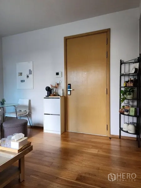 公寓 出租在Watthana, Bangkok - 入户区带木门、小型收纳柜与开放置物架，木地板温馨。