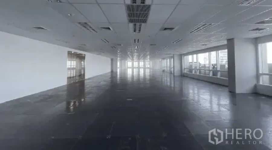 Office Space for rent - Long column-free office floor plate with suspended ceiling, AC vents, and windows on both sides.