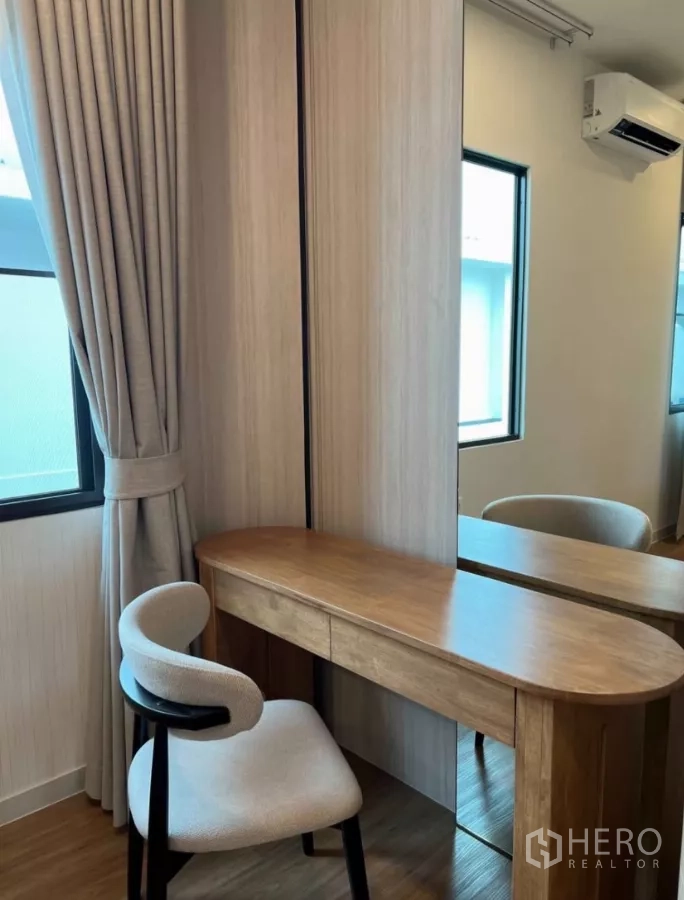 Detached House for rent in Samut Prakan - Dressing table with round-edged wooden desk, mirrored wardrobe and upholstered chair.