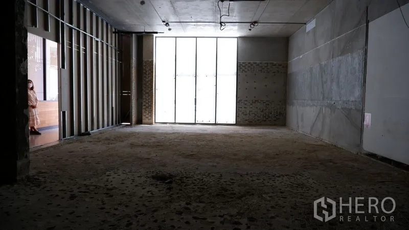 零售空间 出租在Watthana, Bangkok - 进深店铺，前方高挑落地窗，未完工地面与天花。