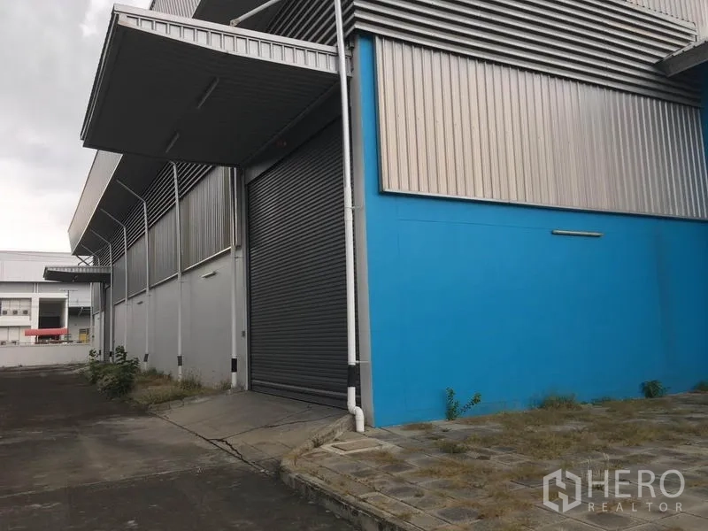 工厂 出租在Samut Prakan - 工厂侧面的有顶装卸区，配大型卷帘门与混凝土坡道。