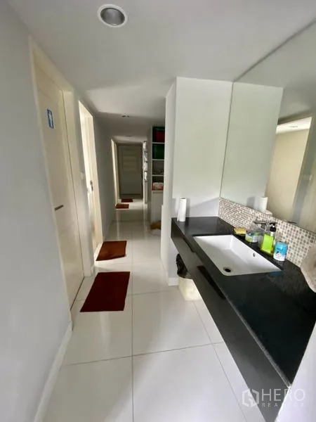 Home Office for rent or sale in Yan Nawa, Bangkok - Clean corridor with white tiles leading to bathrooms and a long vanity sink.