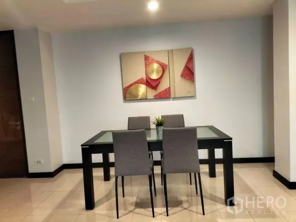 Condominium for rent in Watthana, Bangkok - Minimal dining area with four gray chairs around a black glass-top table and wall art.