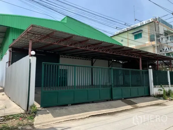 工厂 出租在Pathum Thani - 工厂外观，绿色屋顶与金属滑门，带有遮雨装卸区。