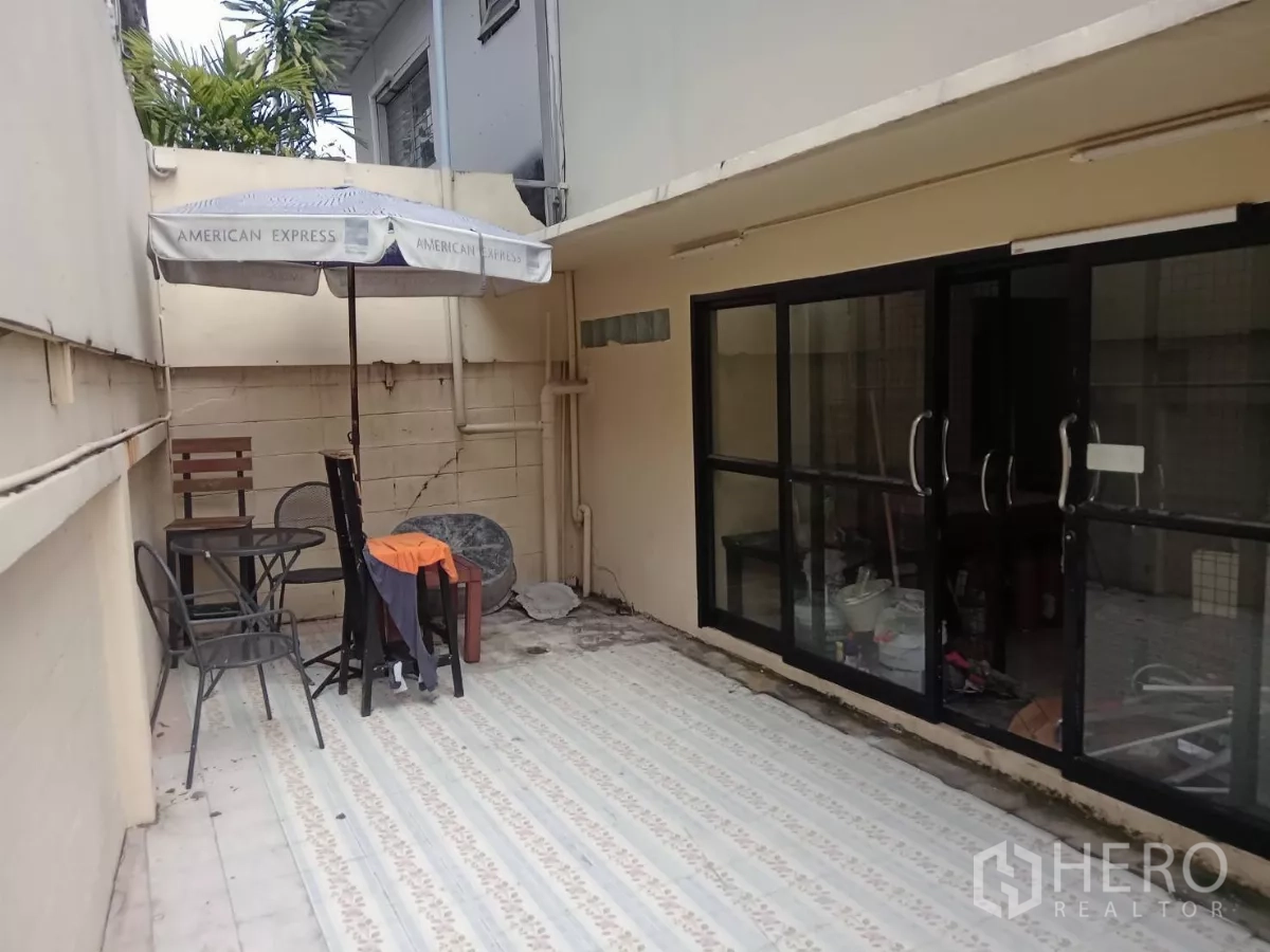 独立式住宅 出租在Phaya Thai, Bangkok - 带滑动玻璃门的室外露台，配遮阳伞和小餐桌椅。