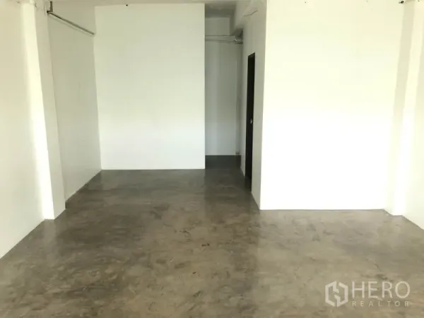 零售空间 出租在Khlong Toei, Bangkok - 白墙店面，水泥地面，后方通道与卫生间入口。