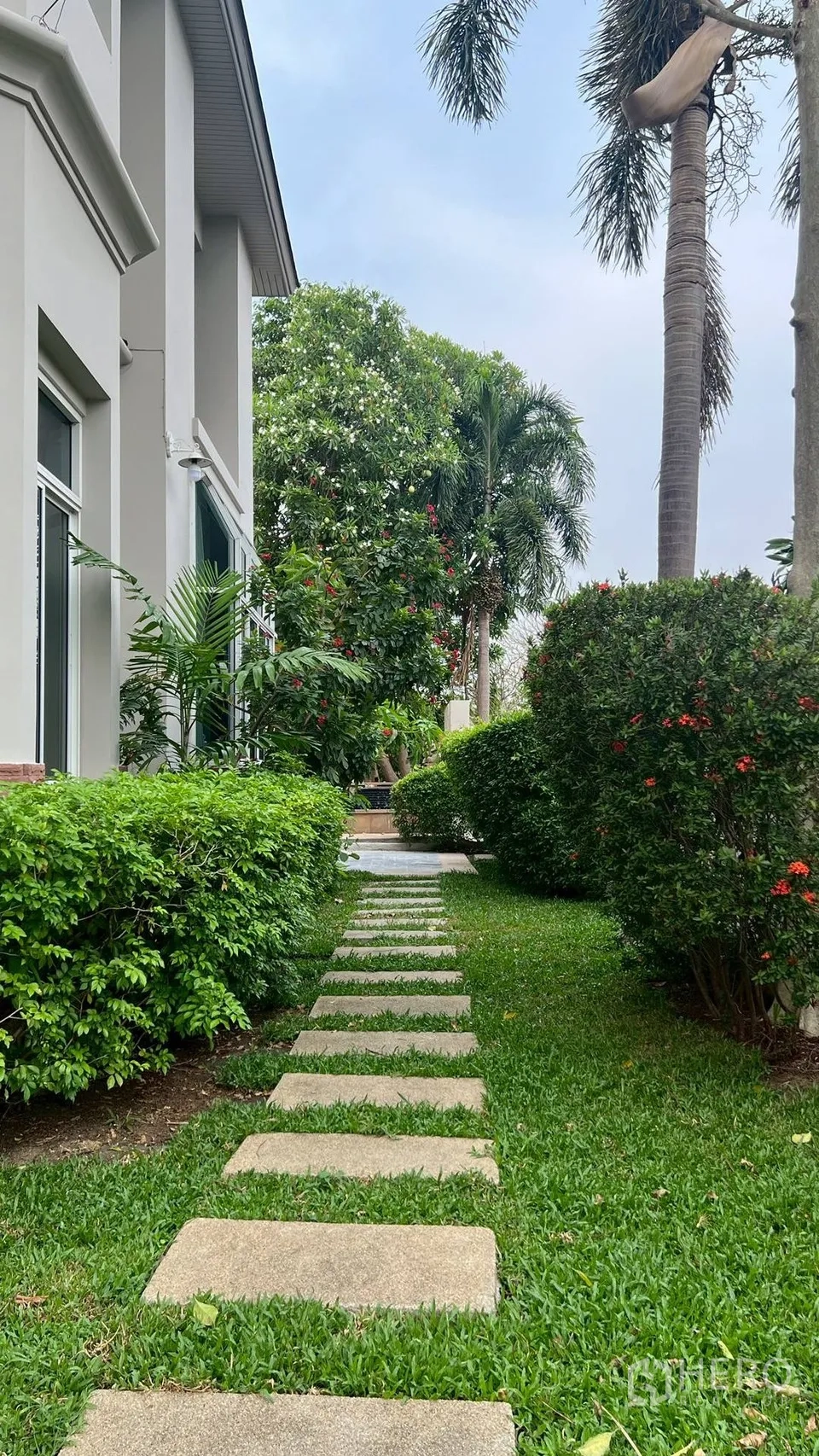 Detached House for rent in Lat Krabang, Bangkok - Side garden walkway lined with trimmed hedges and mature trees.