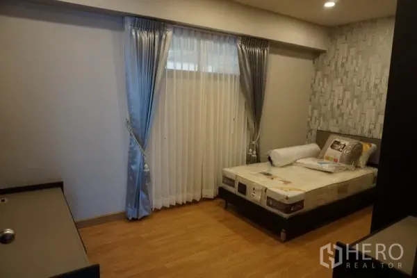 Condominium for rent in Watthana, Bangkok - Second bedroom with single bed, feature wall and floor‑to‑ceiling curtains.