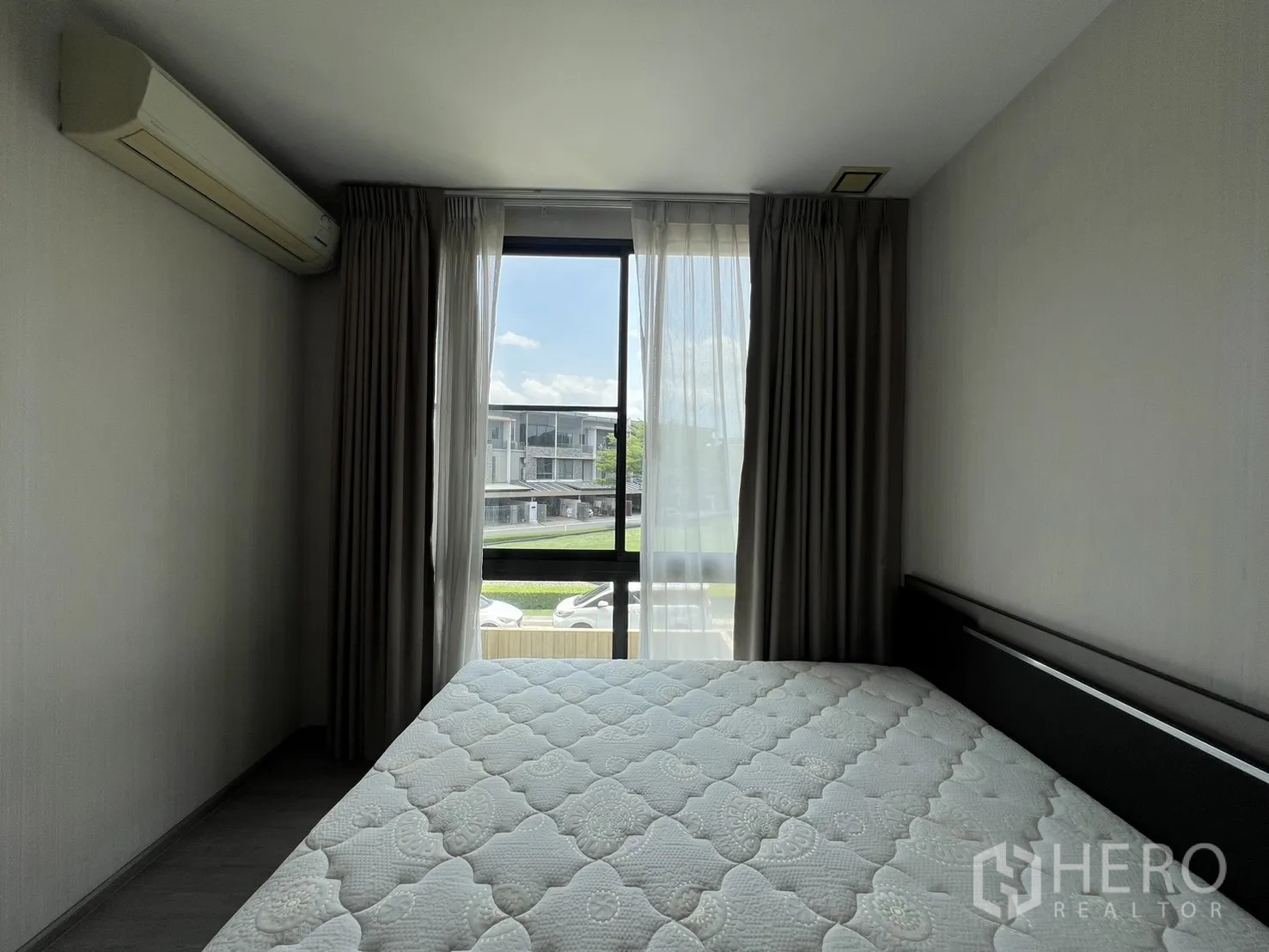 联排别墅 出租在Lat Phrao, Bangkok - 次臥配雙人床、窗簾、分體空調與臨街窗戶。