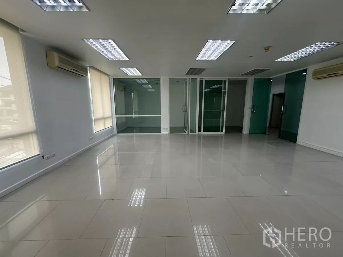 办公空间 出租在Huai Khwang, Bangkok - 开放空间，可见通往独立房间的推拉玻璃门与亮面瓷砖地。