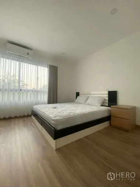 Townhouse for rent in Bang Kapi, Bangkok - Bright master bedroom with queen bed, wood floor, sheer curtains and AC in a Bang Kapi townhouse.