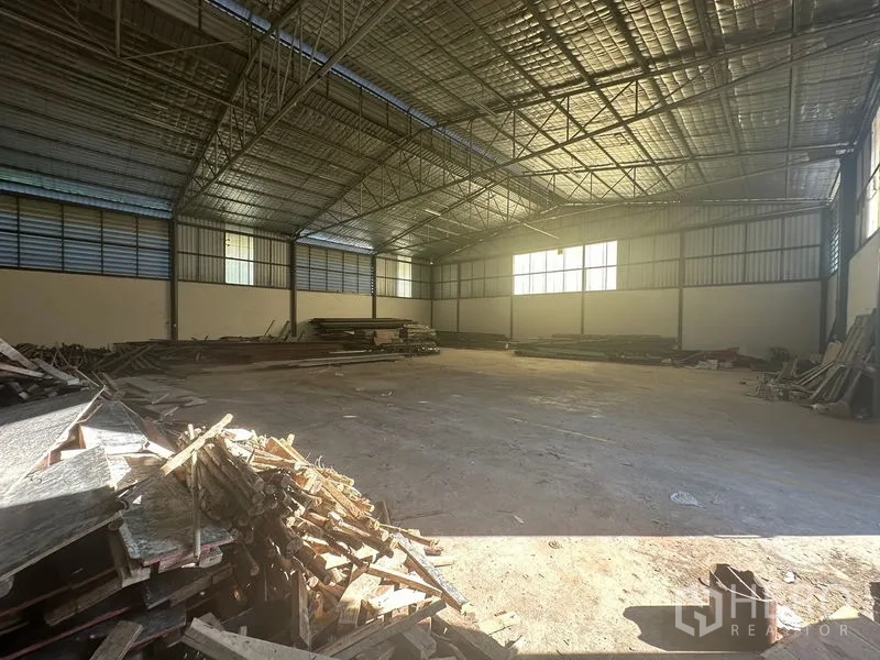 Warehouse for rent in Saphan Sung, Bangkok - Spacious warehouse interior with high steel truss roof, insulated panels, concrete floor and stacked timber.