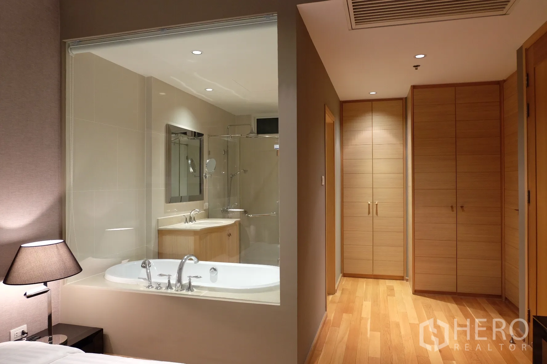 Condominium for rent in Sathon, Bangkok - View of ensuite bathroom with tub and glass shower from bedroom, plus hallway with built-in wardrobes.
