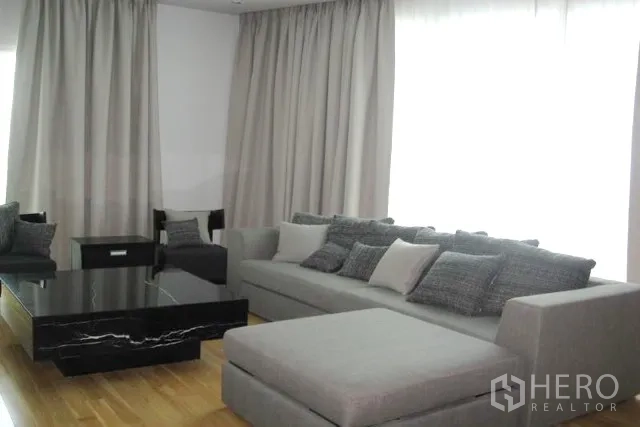 คอนโด ขายในKhlong Toei, Bangkok - โซฟาแอลสีเทาพร้อมหมอน โต๊ะกลางหินสีดำ ใกล้ผ้าม่านเต็มความสูง