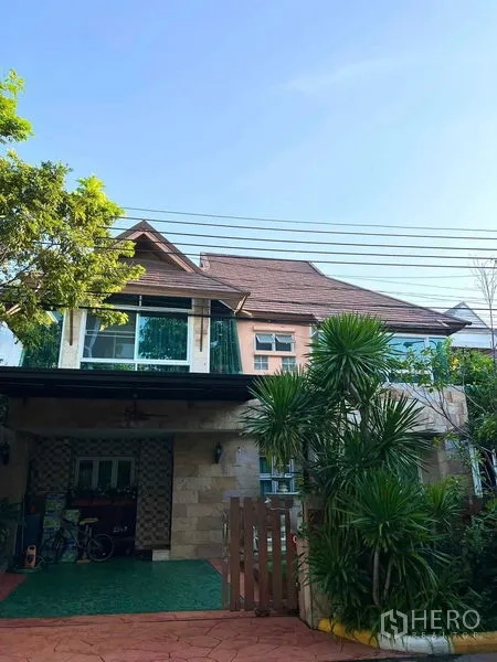 Detached House for sale in Bueng Kum, Bangkok - Two-storey detached house exterior with carport, tiled driveway, and tropical plants.