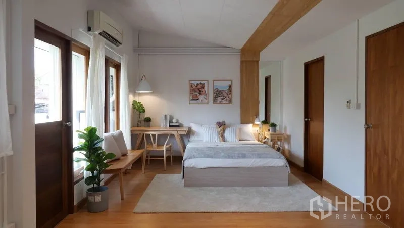 ทาวน์เฮาส์ ให้เช่าในKhlong Toei, Bangkok - ห้องนอนหลักกว้าง มีเตียง โต๊ะทำงาน ประตูกระจกออกระเบียง และต้นไม้ตกแต่ง