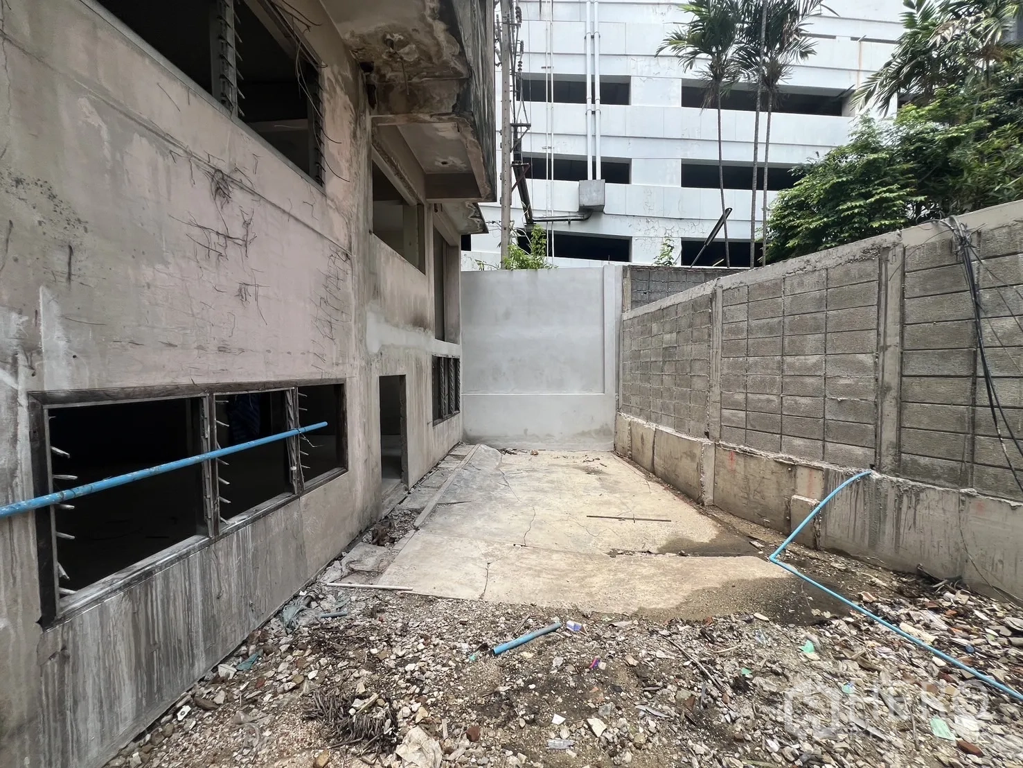 店屋 for rent in Bang Rak, Bangkok - 围墙后的后院，地面粗糙并有管线。