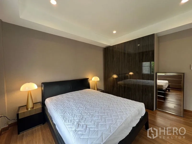 Detached House for sale in Mueang Pathum Thani, Pathum Thani - Cozy bedroom with queen bed, bedside lamps and glossy built-in wardrobe.