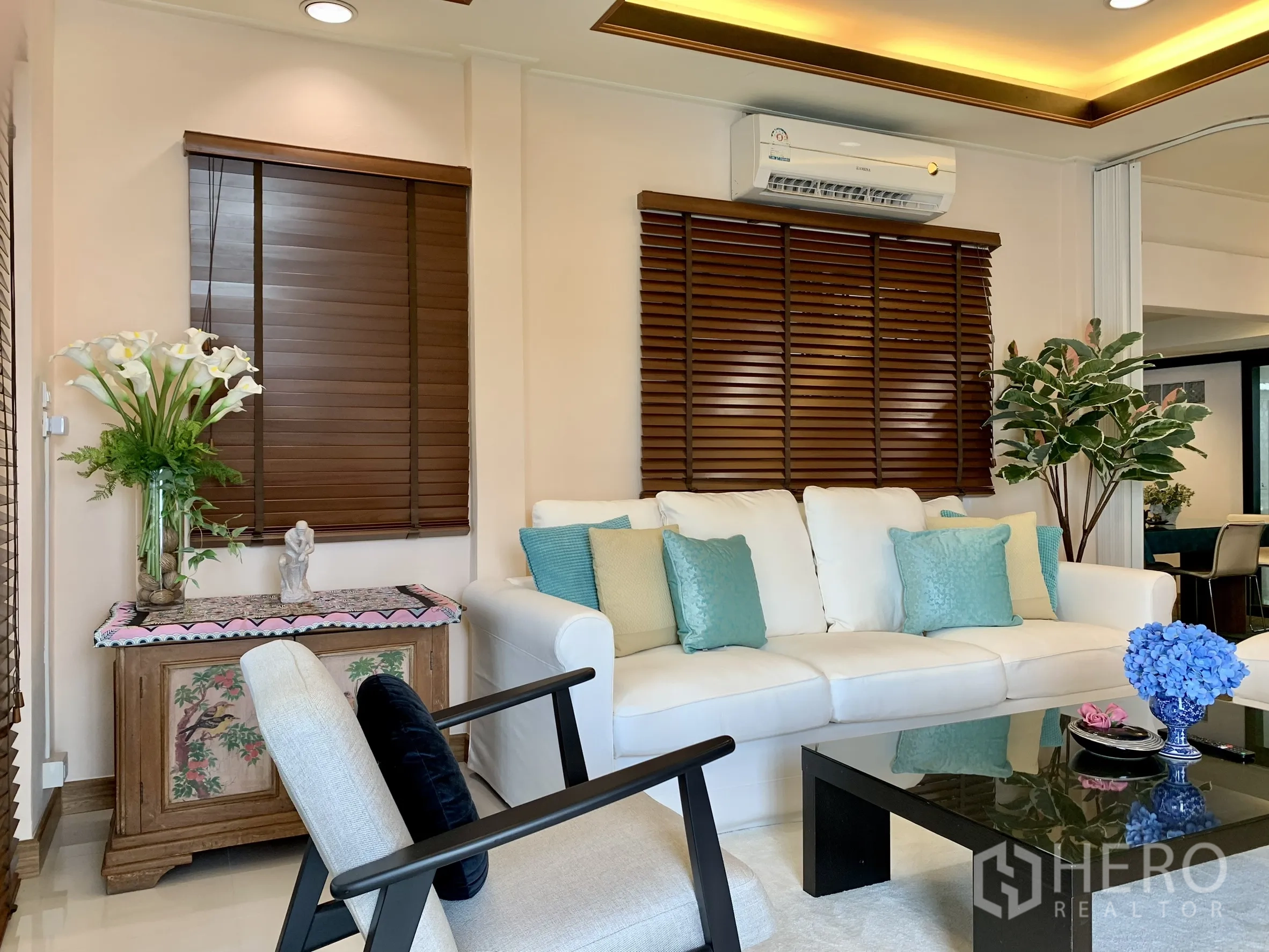 บ้านเดี่ยว for rent in Saphan Sung, Bangkok - มุมมองห้องนั่งเล่นที่มีผนังทีวี ชุดที่นั่ง หน้าต่างบานใหญ่ และไฟเพดานโทนอุ่น.