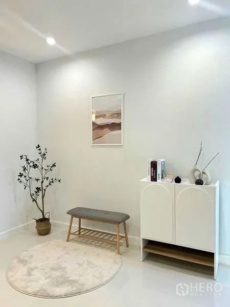 联排别墅 出售在Khlong Toei, Bangkok - 温馨角落，长凳、圆形地毯、窄柜与绿植点缀白墙。