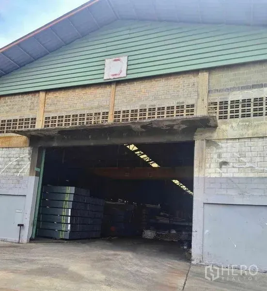 Warehouse for rent in Phra Pradaeng, Samut Prakan - Front gable of the warehouse with masonry facade and stacked steel sheets inside