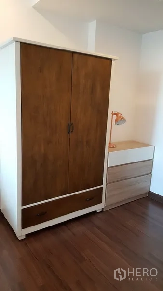 Condominium for rent in Sathon, Bangkok - Freestanding wardrobe and chest of drawers with desk lamp on wood floor.