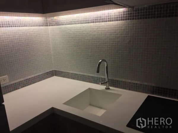 คอนโด ให้เช่าในPhaya Thai, Bangkok - ครัวรูปตัวแอล ท็อปหินสีขาว ไฟใต้ตู้ และผนังกระเบื้องโมเสคพร้อมอ่างล้างจานและเตา