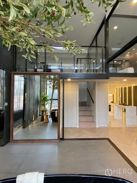 Detached House for sale in Watthana, Bangkok - Entryway with oversized mirror, indoor greenery, and stairs leading to the mezzanine.