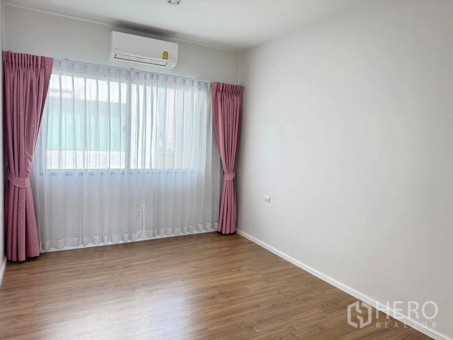 Townhouse for rent in Saphan Sung, Bangkok - Empty secondary bedroom with pink curtains, wood floor and air conditioner.
